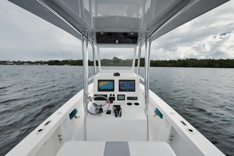 Slide: The Image of 2024 Rambo 27 boat cockpit with steering wheel and navigation screens on open water. - 2