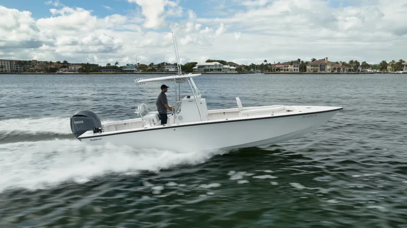 Slide: The Image of 2024 Rambo 27 boat cruising on a scenic waterway under a partly cloudy sky. - 37
