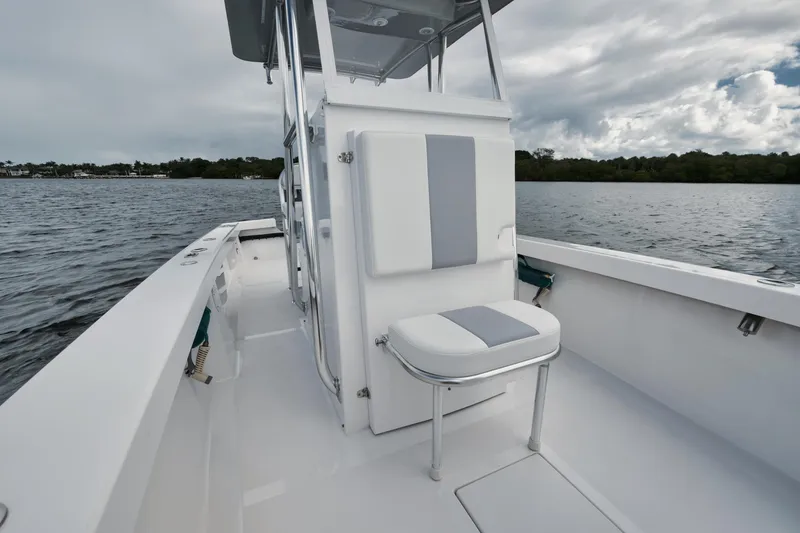 Slide: The Image of 2024 Rambo 27 boat interior with seating, on a calm lake under cloudy skies. - 8