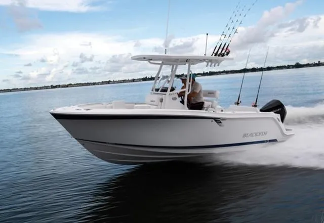 Slide: The Image of 2024 Blackfin 222CC boat cruising on calm water with fishing rods. - 2