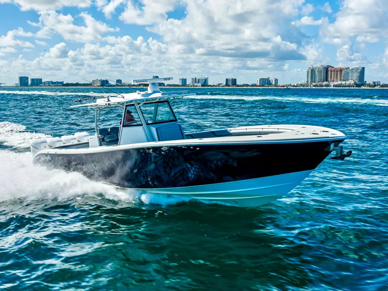 Slide: The Image of 2021 Yellowfin 39 boat cruising on open water with city skyline in background. - 2