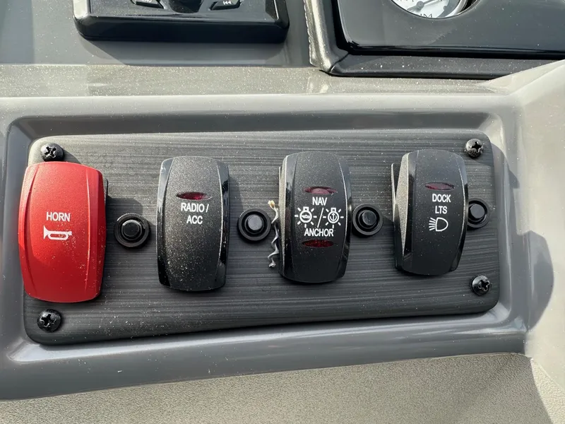 Slide: The Image of Control panel of 2024 Bennington 20 SSR Quad Bench with horn, radio, navigation, and dock lights switches. - 20