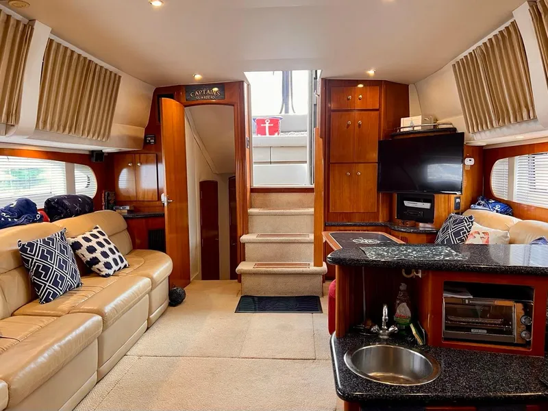 Slide: The Image of Interior of a 2000 Carver 396 Motor Yacht with beige leather seating and wooden cabinetry. - 21