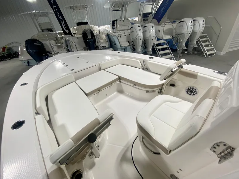 Slide: The Image of 2026 Robalo 246 Cayman boat interior with white seating and steering wheel in showroom. - 21