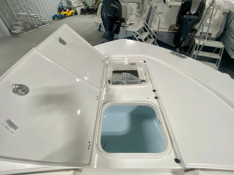 Slide: The Image of 2026 Robalo 246 Cayman boat storage compartments open in a showroom. - 26