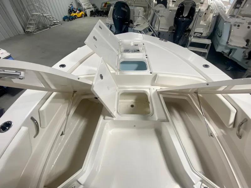 Slide: The Image of 2026 Robalo 246 Cayman boat interior with open storage compartments in a showroom. - 28