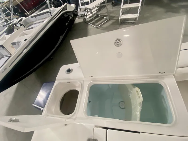Slide: The Image of 2026 Robalo 246 Cayman boat with open storage compartments in a showroom. - 9
