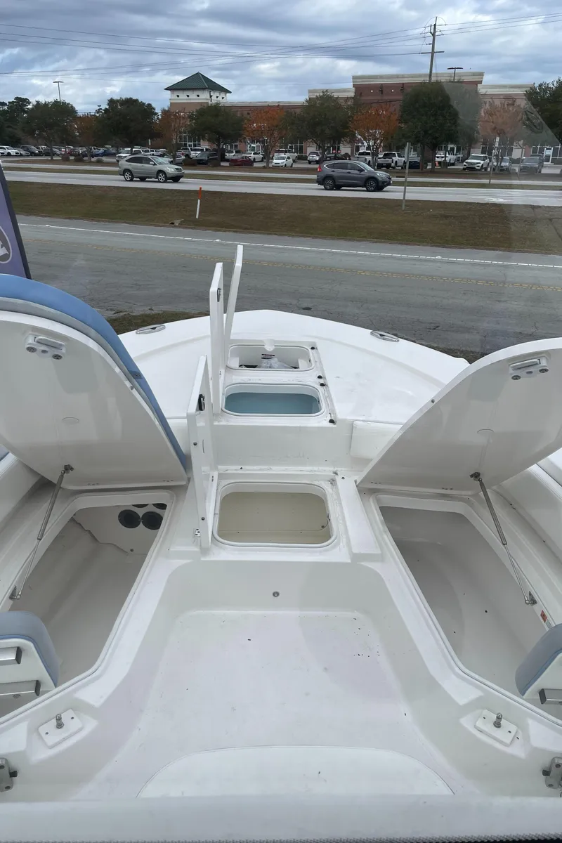 Slide: The Image of 2026 Robalo 246 Cayman boat with open storage compartments, parked near a road. - 14