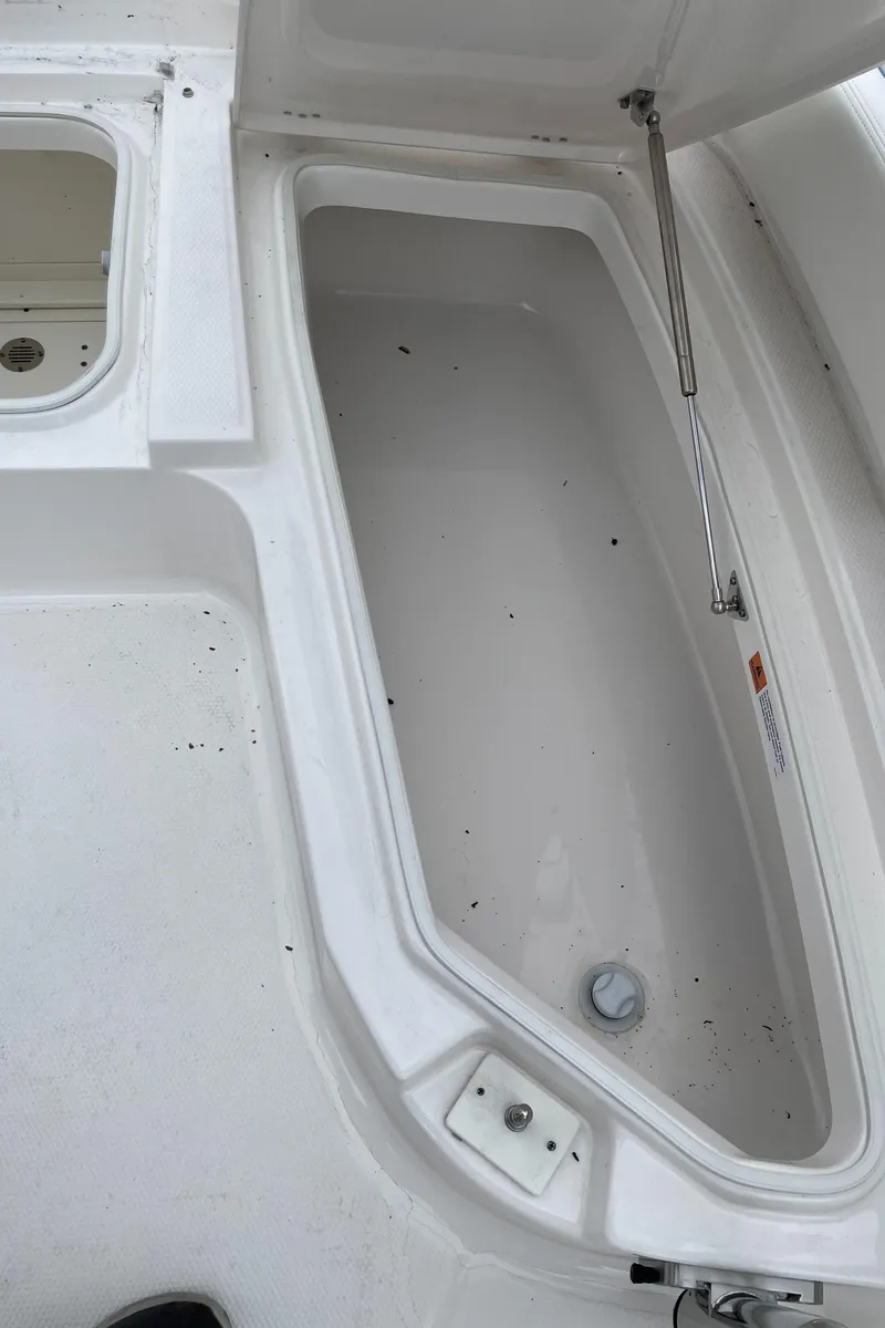 Slide: The Image of 2026 Robalo 246 Cayman storage compartment with open lid, showcasing spacious interior design. - 17