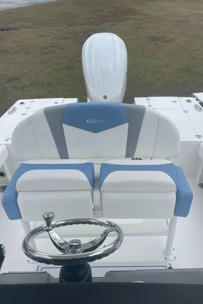 Slide: The Image of 2026 Robalo 246 Cayman boat interior with blue and white seating and steering wheel. - 6