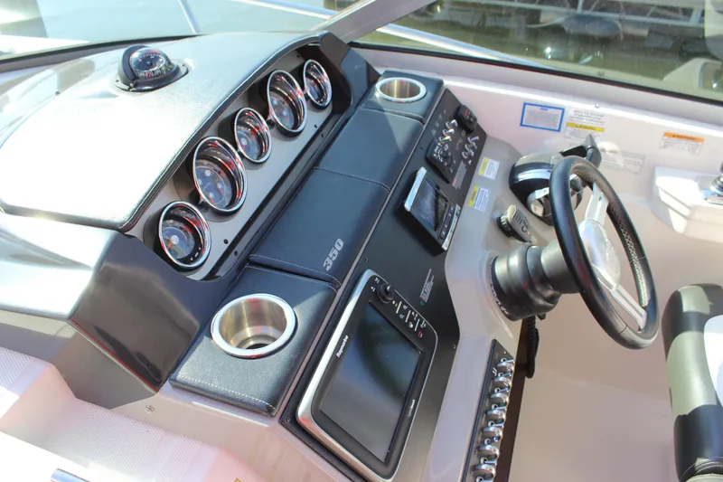Slide: The Image of 2014 Sea Ray 350 Sundancer helm with gauges, steering wheel, and controls. - 26