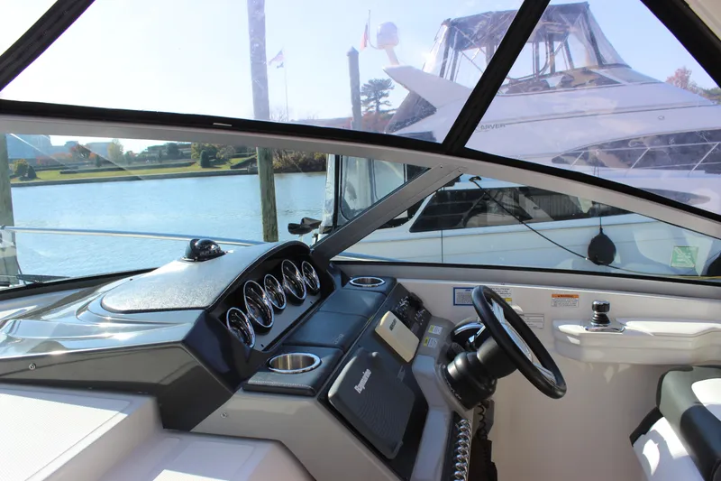 Slide: The Image of 2014 Sea Ray 350 Sundancer helm with gauges and steering wheel, docked by the water. - 34