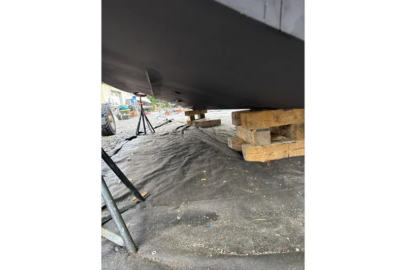 Slide: The Image of 2014 Sea Ray 350 Sundancer boat hull on wooden blocks, outdoor maintenance setting. - 74