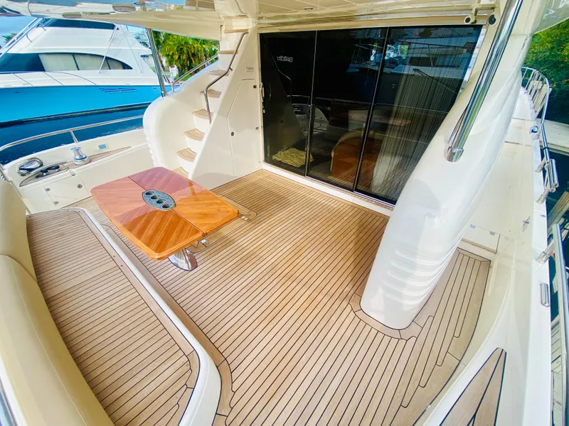 Slide: The Image of 2006 Viking Sport Cruisers 70 Motor Yacht aft deck with teak flooring and wooden table. - 11