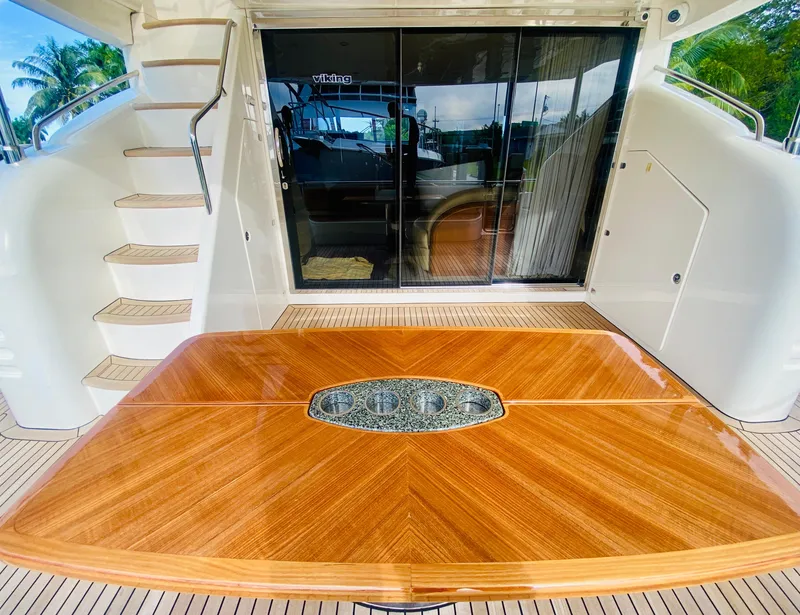 Slide: The Image of 2006 Viking Sport Cruisers 70 Motor Yacht aft deck with wooden table and staircase. - 13