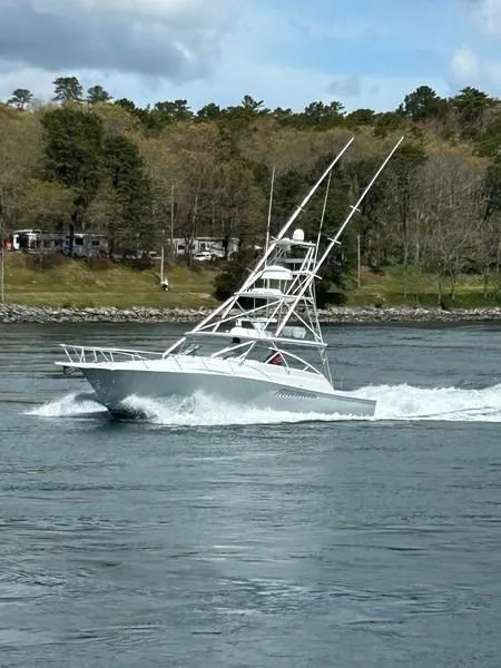 Slide: The Image of 2005 Viking 45 Open Express cruising on a lake with a forested shoreline. - 1