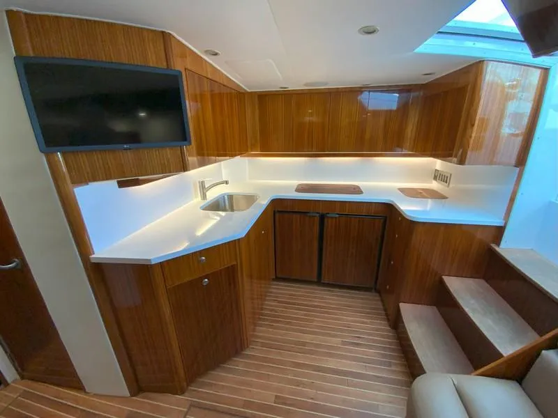 Slide: The Image of 2005 Viking 45 Open Express yacht kitchen with modern wood cabinetry and white countertops. - 49