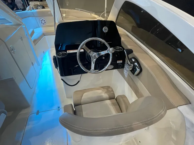 Slide: The Image of 2024 Scout 240 Dorado boat helm with modern steering wheel and illuminated interior. - 7