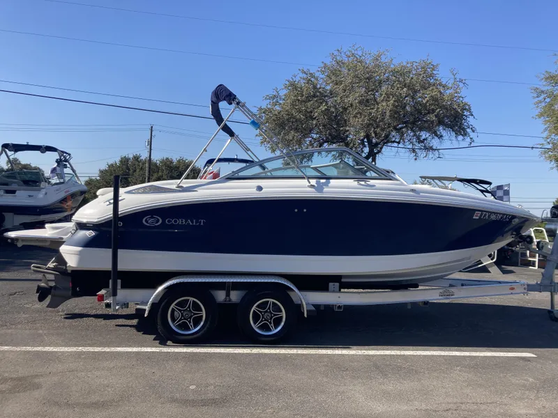 The Image of 2007 Cobalt 212 boat on trailer, parked outdoors under clear blue sky. - 1