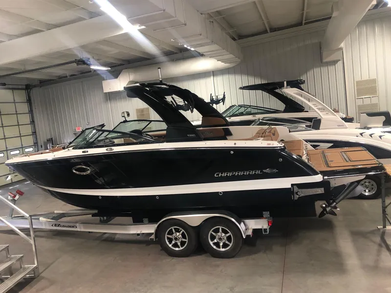 The Image of 2024 Chaparral 28 Surf boat in showroom, black exterior, on trailer. - 0
