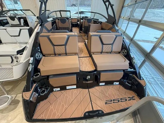 Slide: The Image of 2025 Yamaha Boats 255XD interior with tan seating and sleek design in showroom. - 4