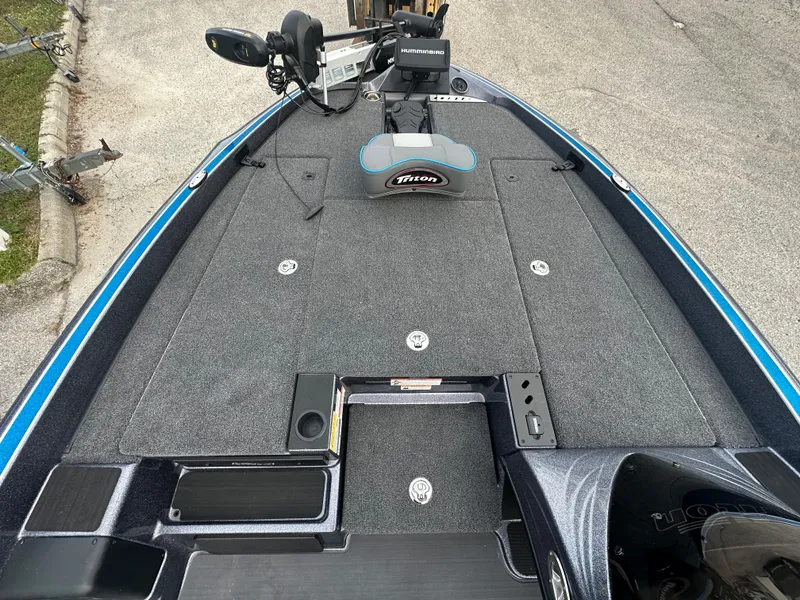 Slide: The Image of 2024 Triton 18 TrX fishing boat deck with trolling motor and storage compartments. - 5