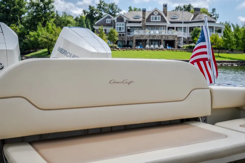 Slide: The Image of 2024 Chris-Craft Calypso 35 boat with American flag, luxury waterfront home in background. - 13