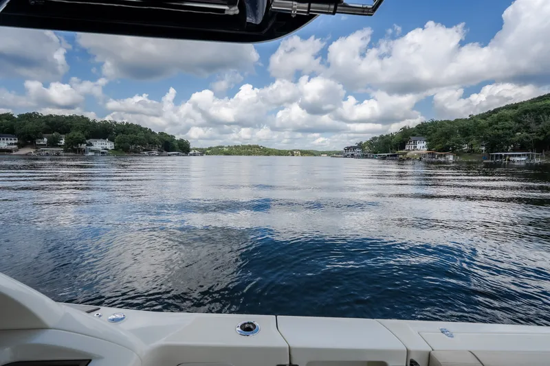 Slide: The Image of 2024 Chris-Craft Calypso 35 on serene lake with lush shoreline and cloudy sky. - 26