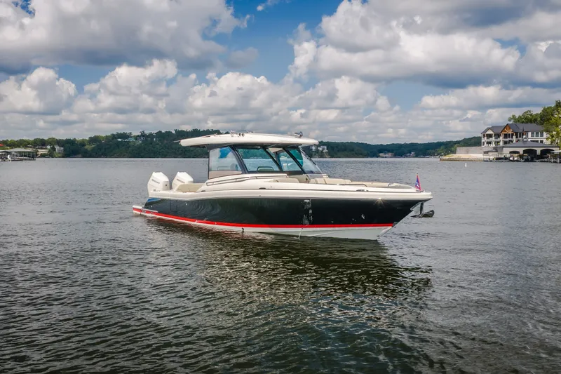 Slide: The Image of 2024 Chris-Craft Calypso 35 boat on a serene lake under a partly cloudy sky. - 17