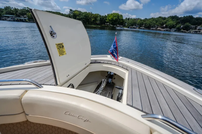 Slide: The Image of 2024 Chris-Craft Calypso 35 boat with open storage hatch on a serene lake. - 51