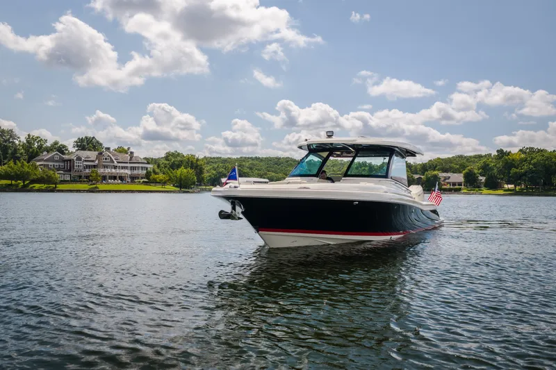 Slide: The Image of 2024 Chris-Craft Calypso 35 boat cruising on a scenic lake with a luxurious house in the background. - 19
