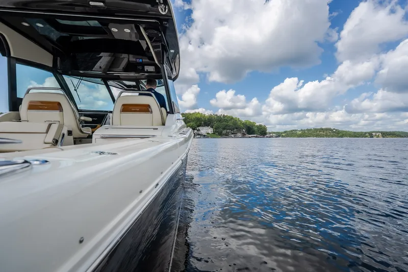 Slide: The Image of 2024 Chris-Craft Calypso 35 on serene lake with cloudy sky backdrop. - 8
