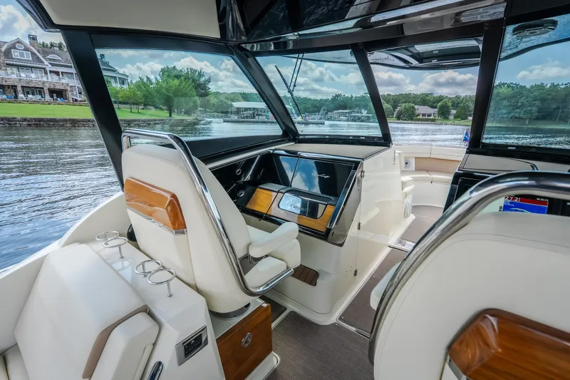 Slide: The Image of 2024 Chris-Craft Calypso 35 interior with luxurious seating and modern dashboard on a scenic lake. - 39