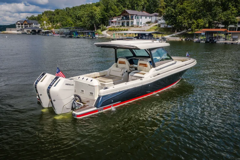Slide: The Image of A sleek 2024 Chris-Craft Calypso 35 boat on a calm lake with wooded shoreline. - 2