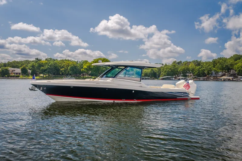 Slide: The Image of 2024 Chris-Craft Calypso 35 boat on a serene lake with lush green shoreline. - 16