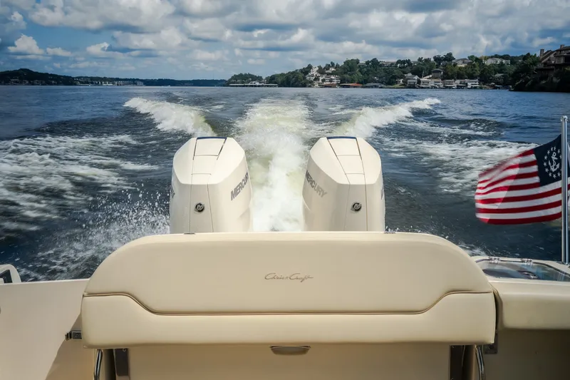 Slide: The Image of 2024 Chris-Craft Calypso 35 cruising on a lake with American flag and twin Mercury engines. - 14