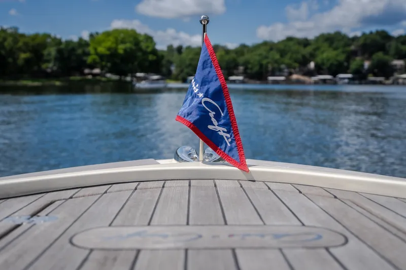 Slide: The Image of 2024 Chris-Craft Calypso 35 boat with flag on deck, scenic lake view. - 50