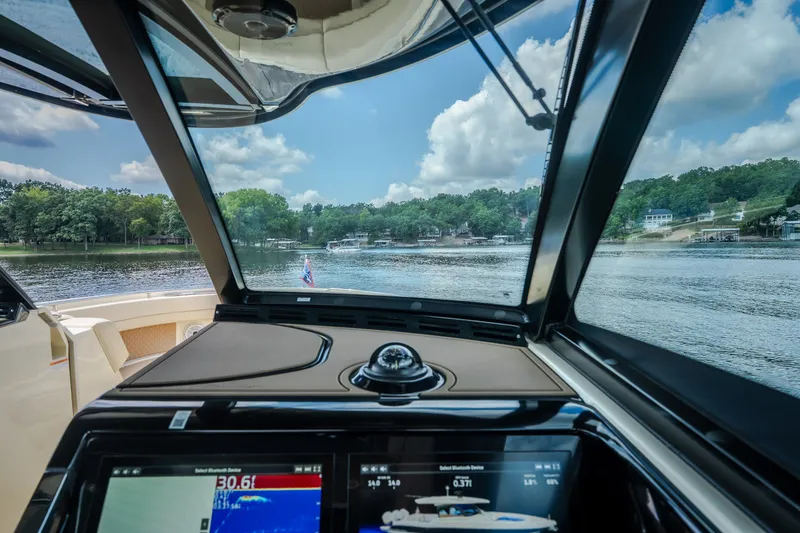 Slide: The Image of 2024 Chris-Craft Calypso 35 cockpit view with navigation screens, overlooking serene lake and shoreline. - 36