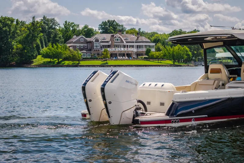 Slide: The Image of 2024 Chris-Craft Calypso 35 boat on a serene lake with a luxurious house in the background. - 7