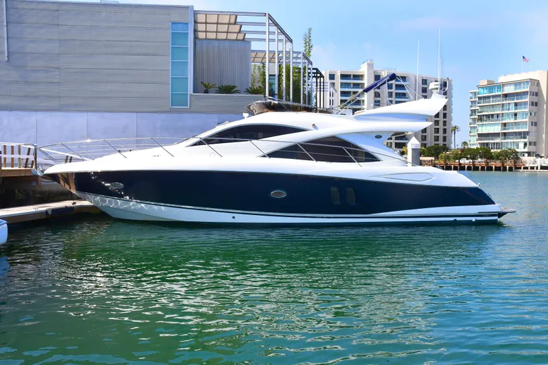 Slide: The Image of 2006 Sunseeker Manhattan 50 yacht docked in a marina, modern architecture in the background. - 0
