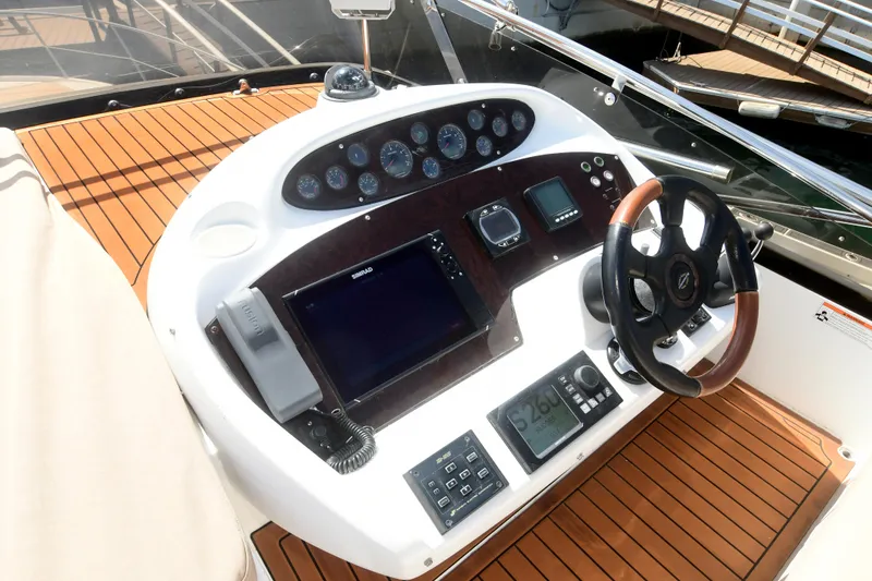 Slide: The Image of 2006 Sunseeker Manhattan 50 yacht helm with modern navigation controls and wooden accents. - 38