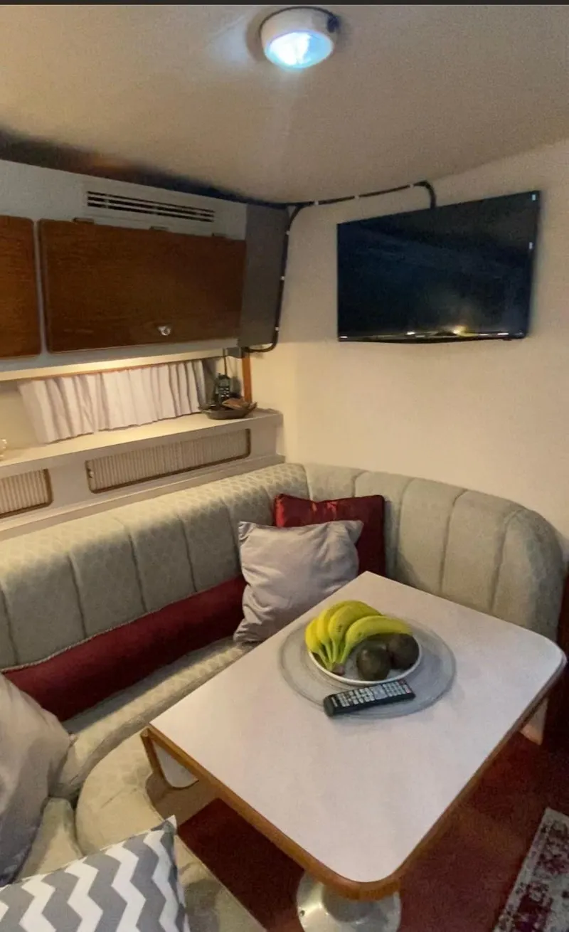 Slide: The Image of 1992 Regal Commodore 400 boat interior with cozy seating, TV, and dining table. - 15