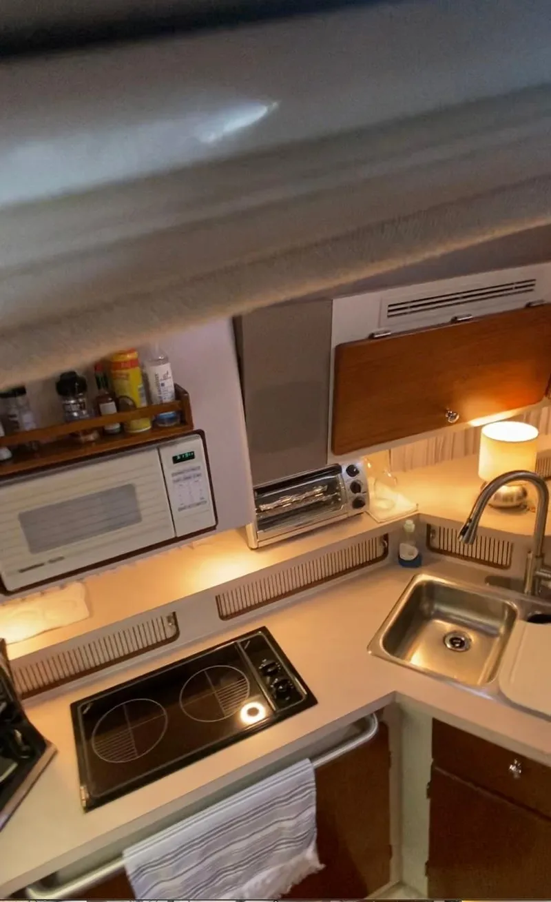 Slide: The Image of Compact kitchen area in a 1992 Regal Commodore 400 boat with stove, sink, and microwave. - 16