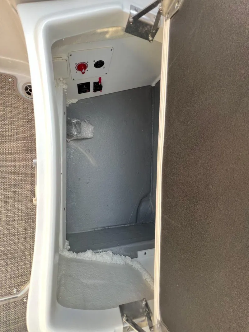 Slide: The Image of 2024 Crownline 270 SS storage compartment with control panel and carpeted interior. - 15