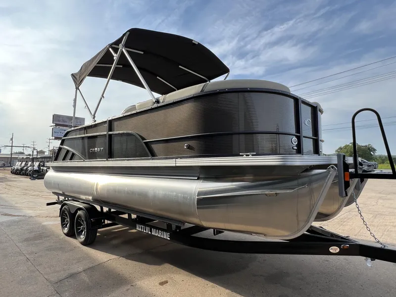 Slide: The Image of 2023 Crest Classic LX 220 SLS pontoon boat with canopy on trailer, outdoor setting. - 6