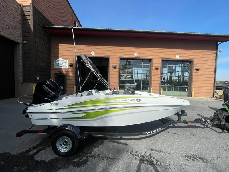 Slide: The Image of 2024 Tahoe T16 boat on trailer, parked outside a garage under clear blue sky. - 3
