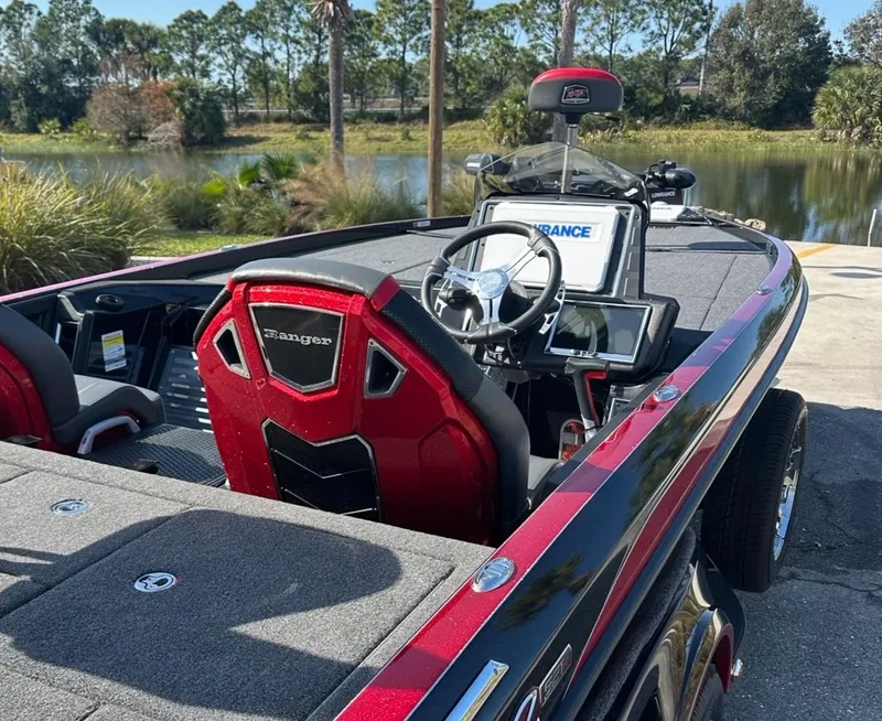 Slide: The Image of 2024 Ranger Z521R Ranger Cup Equipped boat, red and black interior, near a scenic lake. - 4