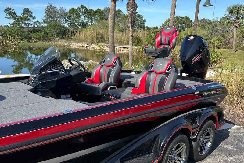 Slide: The Image of 2024 Ranger Z521R Cup Equipped boat with red and black seats by a lake. - 6