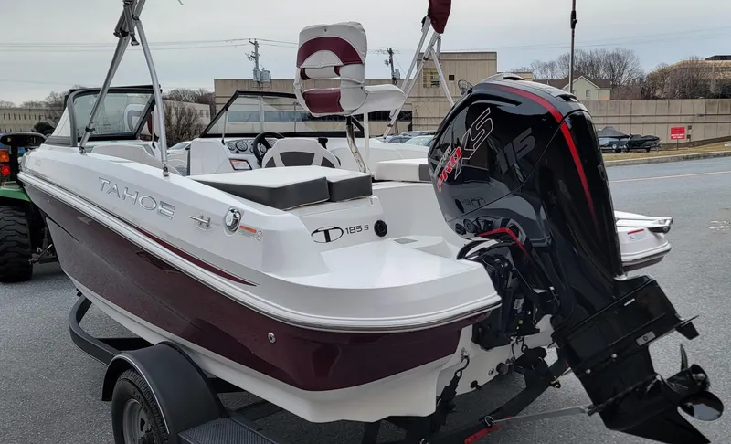 Slide: The Image of 2024 Tahoe 185 S boat with outboard motor on a trailer, parked outdoors. - 3