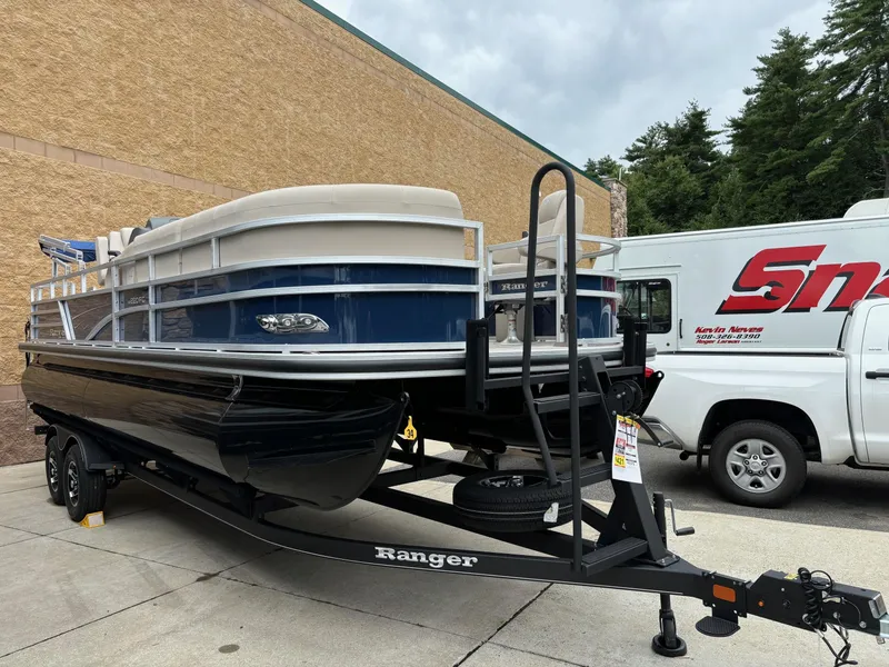 Slide: The Image of 2024 Ranger Reata 220FC pontoon boat on trailer, parked outdoors. - 2